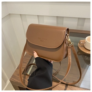 Détail du sac en cuir marron avec boucle dorée et logo Tidal Dryness embossé