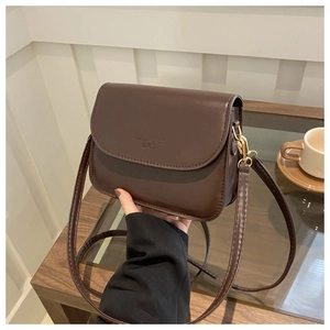 Détail du sac à rabat en cuir mat marron foncé avec logo embossé et boucles dorées