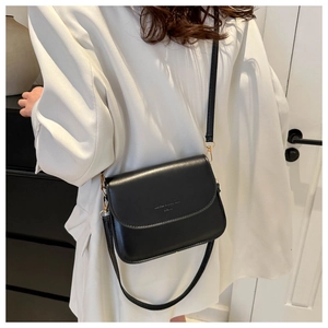 Détail d'un sac bandoulière vintage noir avec garniture dorée porté par un mannequin