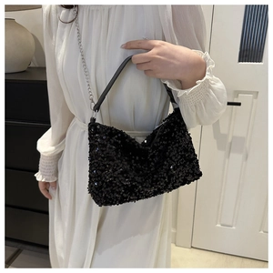 Detail of black sequin crossbody bag with silver chain strap shown on white dress