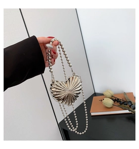 Macro shot of silver heart-shaped clutch bag with radiant pleated texture and bead chain