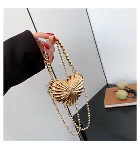 Detail view of heart-shaped gold clutch with radiant pleated texture and bead chain