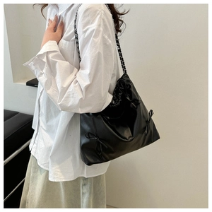 Détail de la surface en cuir noir brillant et du nœud décoratif sur le sac porté épaule