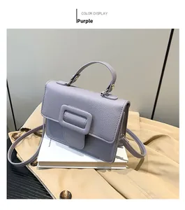 Détail du petit sac violet en cuir avec boucle carrée posé sur un trench-coat classique