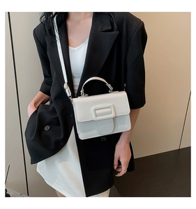 Détail d'un petit sac carré blanc en cuir grainé avec boucle décorative et bandoulière fine