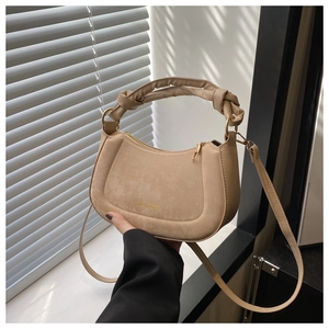 Detail of beige saddle bag featuring knot handle and golden SENLL JEWYNEES logo