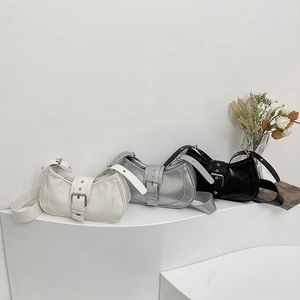 Trois sacs à bandoulière demi-lune en blanc, argent et noir sur un présentoir blanc épuré