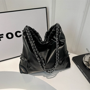 Grand sac cabas noir en similicuir avec bandoulière chaîne et nœuds sur fond blanc