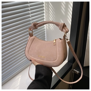 Detail of pink half-moon handbag featuring knotted handle and gold Time Myself logo
