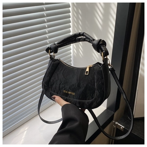 Detail of black pleated hobo bag with gold Tidal Dryness logo and knotted handle design