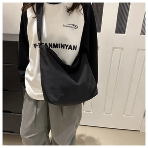 Gros plan d'un sac hobo noir à large bandoulière porté par un mannequin en intérieur
