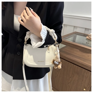 Close-up of ivory saddle bag with unique knotted handle and cute plush eye charm