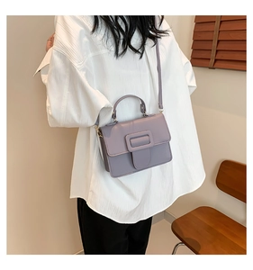 Détail du sac à bandoulière lilas avec cuir texturé et boucle sur une chemise blanche