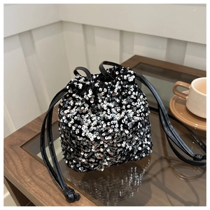 Close-up of sparkling silver sequins on bucket bag with black drawstring and leather strap