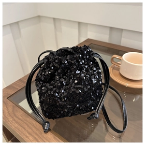 Close-up of black sequin mini bucket bag with drawstring closure and leather strap
