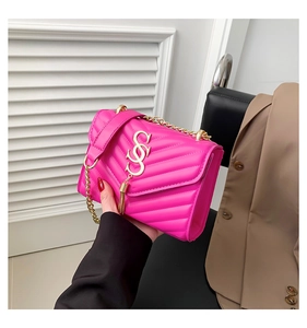 Close-up of fuchsia quilted handbag with gold tassel and chain strap in a fashion setting