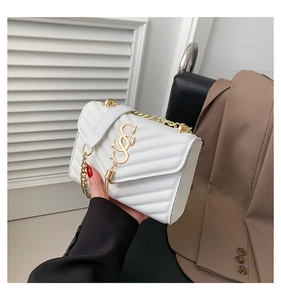 Detail of white quilted crossbody bag with gold chain strap and metal tassel logo