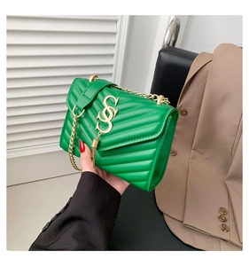 Close-up of green crossbody bag with V-shaped quilting and gold metal chain strap