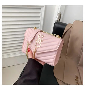 Detailed view of pink quilted handbag with gold logo tassel and chain strap