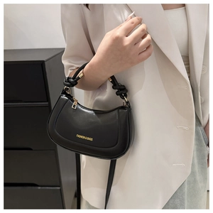 Detail of a black semi-moon bag featuring a knotted handle and golden metal buckles