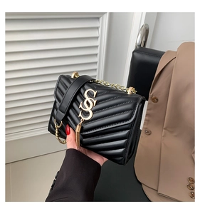 Detail of black quilted leather square bag with gold chain strap and tassel charm