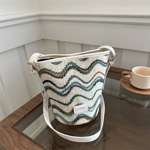 Chic wave patterned knit bucket bag with leather shoulder strap and fashion label detail