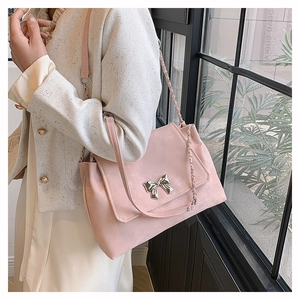Detailed shot of pink tote bag featuring a silver bow charm and mixed chain strap