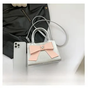 Petit sac argenté avec nœud rose et strass en cœur présenté sous un angle de 45 degrés
