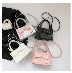 Top view of four bow-accented crossbody bags in pink, white, black, and silver shades