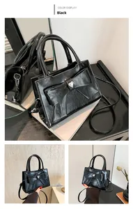 Detail of black patent leather handbag with oversized bow and crystal heart center