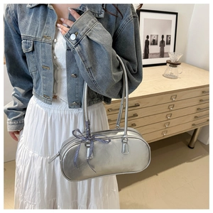 Silver matte oval handbag with a blue checkered bow accessory in a modern home setting