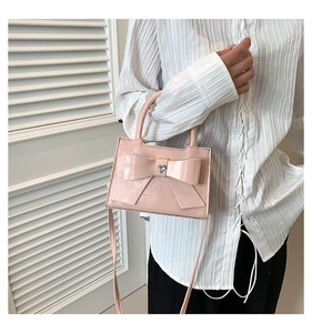 Mannequin portant un mini sac bandoulière rose avec grand nœud et strass en cœur