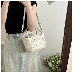 Détail du sac à main en paille tressée avec broderie florale et finitions en cuir PU