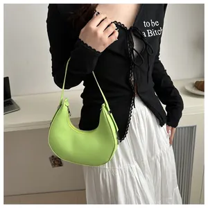 Detail of neon green crescent moon shoulder bag with glossy finish and silver zipper