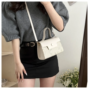 Detail of white woven crossbody bag with leather flap and strap on a model's arm