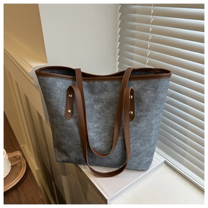 Detail of large grey tote bag with brown leather handles and decorative rivets