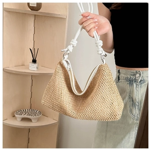 Close-up of woven straw handbag with white leather knotted strap and silver hardware