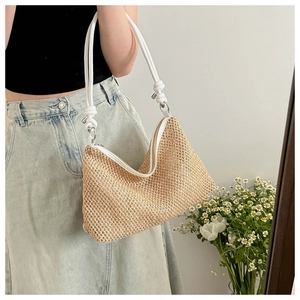 Detail of woven straw tote bag with white leather straps and knot accents on model