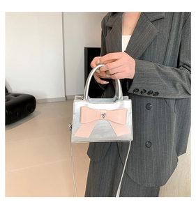 Détail d'un mini sac argenté en PU avec un grand nœud rose et un cristal en cœur