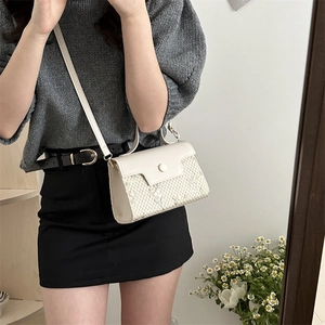 Elegante borsa beige a tracolla intrecciata indossata da una modella in stile moderno