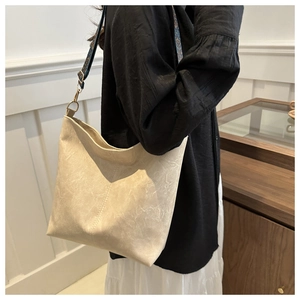 Detail view of beige tote bag with textured surface and ethnic jacquard wide strap