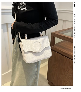 Close-up of stylish white crocodile pattern leather handbag shown on model's shoulder