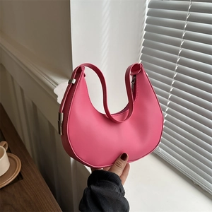 Pink crescent hobo shoulder bag with silver buckle in a sunlit lifestyle setting