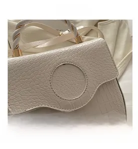 Detail of white crocodile pattern handbag with spiral braided handle and gold hardware