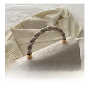 Detailed view of crocodile pattern leather with two-tone twisted handle and gold hardware
