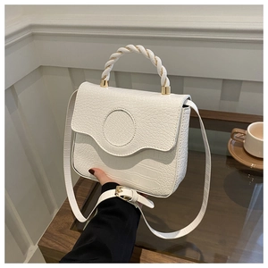 Detail of white crocodile pattern handbag with twisted handle and golden hardware buckle