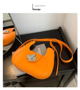 Détail du sac selle orange montrant la grande boucle fleur en argent et le cuir PU