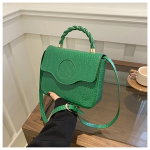 Detail showing vivid green croc-embossed texture and unique spiral twist handle design
