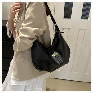 Sac fourre-tout chic en cuir noir porté par un mannequin en tailleur beige élégant
