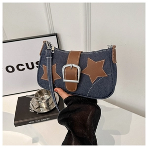 Detailopname van denim schoudertas met sterrenpatches en lederen riemgesp decoratie